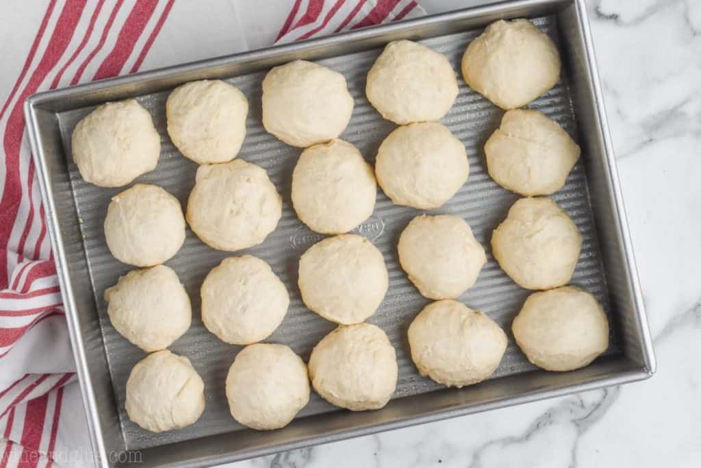 an overhead picture of a metal 9 by 13 inch baking dish filled with 20 dough balls for easy dinner rolls