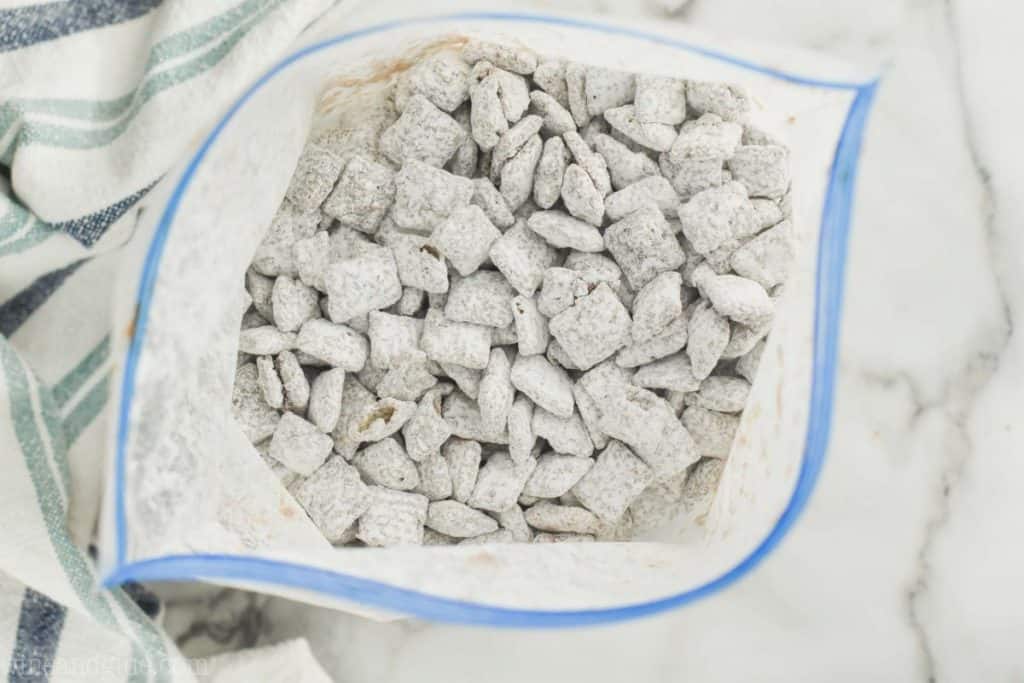 overhead view of muddy buddies in a plastic zip locked bag after they have been tossed with powdered sugar