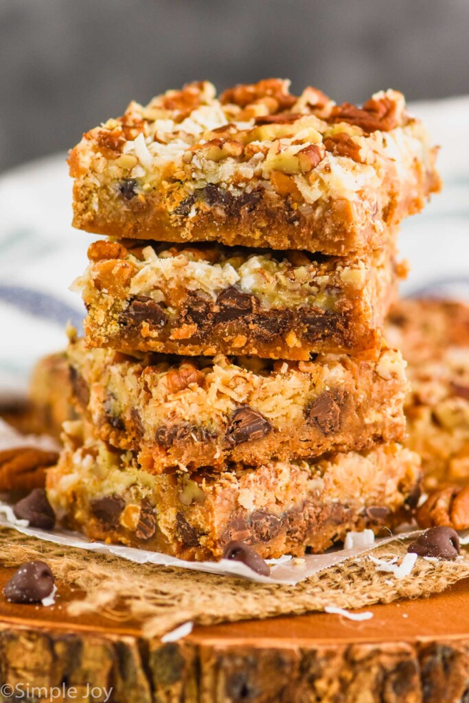 a stack of four magic bars, layer of graham cracker, chocolate chip, coconut, and pecan pieces visible