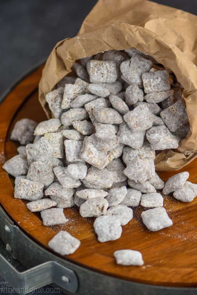 muddy buddies being poured out of a paper bag onto a wood platter