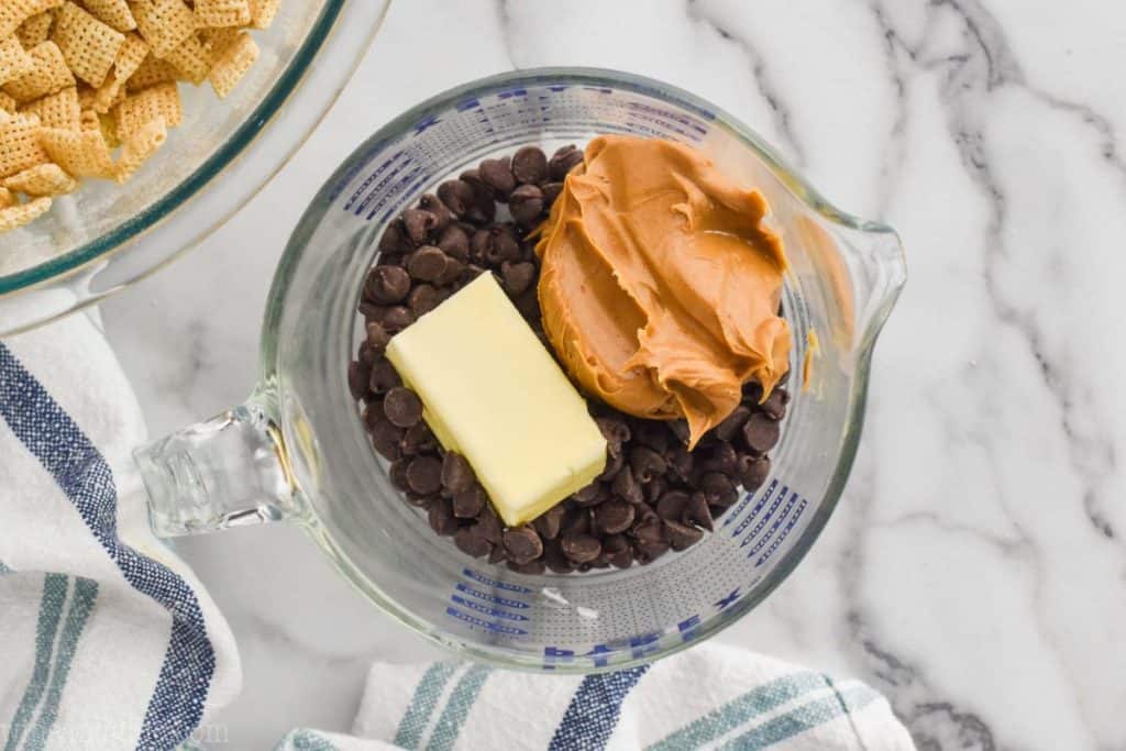 overhead view of a measuring cup with chocolate chips, peanut butter, and half a stick fo butter