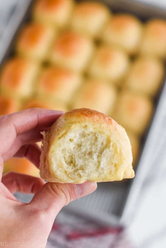 a hand holding an easy dinner roll with the rest of the pan blurred in the background