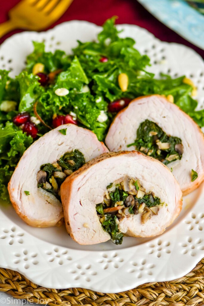 bacon and spinach stuffed pork tenderloin on a white plate with a winter salad