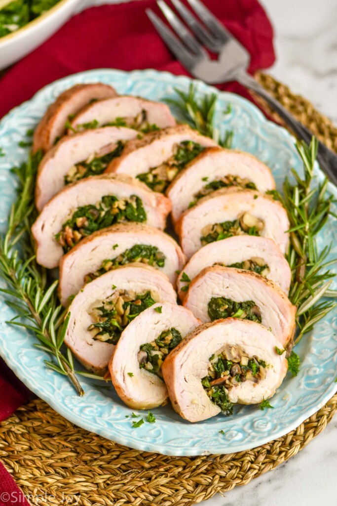 a blue serving platter full of slices of stuffed pork tenderloin