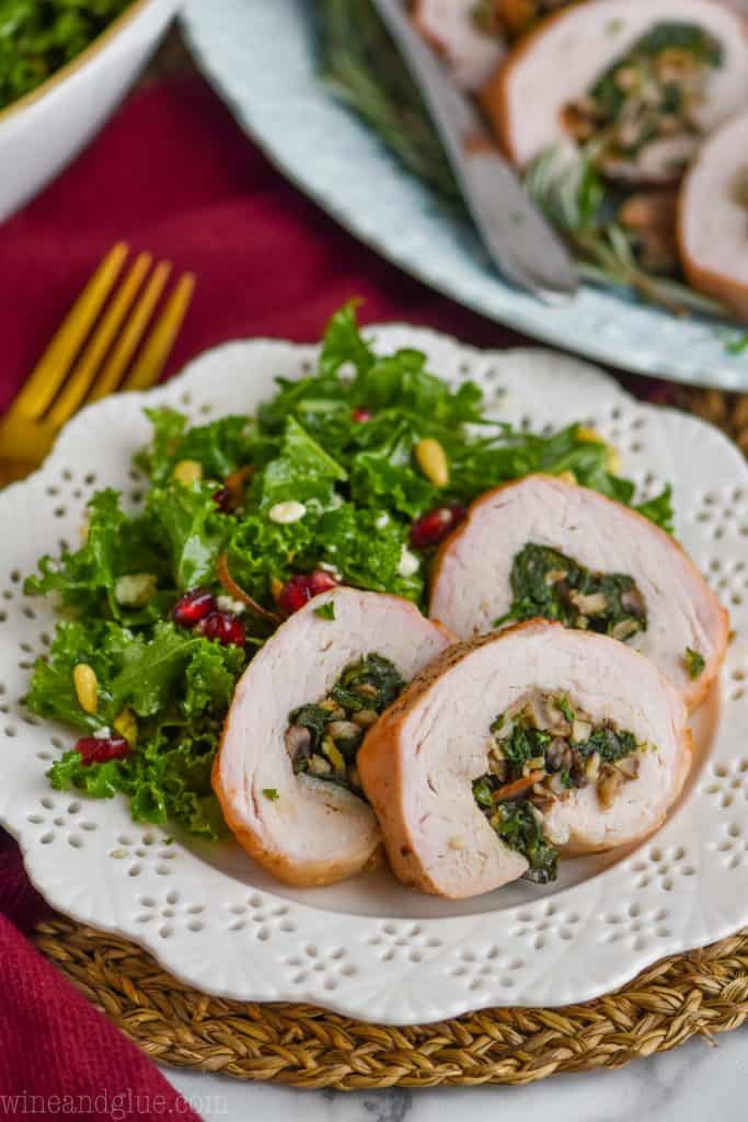 bacon and spinach stuffed pork loin on a white plate with a winter salad