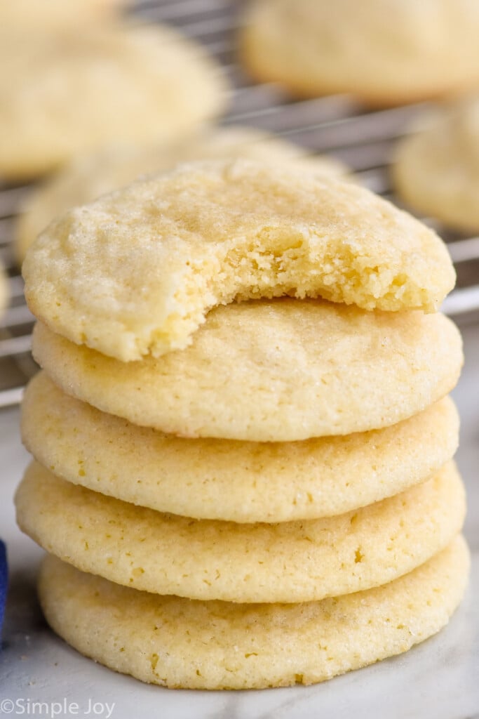 a stack of five sugar cookies with a bite missing out of the top one