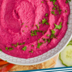pinterest graphic of overhead view of a white bowl full of bright pink beet hummus garnished with fresh parsley, says: beet hummus simplejoy.com