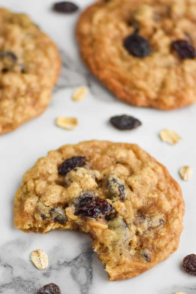 close up of an oatmeal raisin cookie on a marble surface with a bite missing