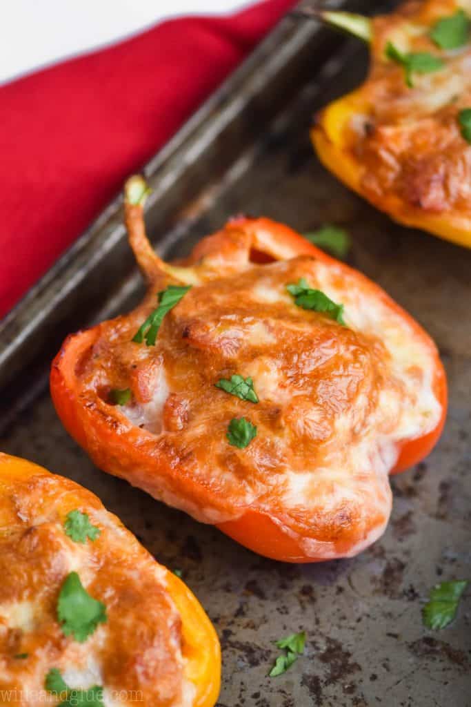 a red bell pepper, half pepper that has been stuffed and is covered with brown bubbly cheese