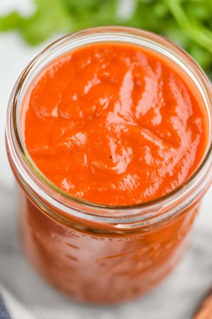 close up overhead of thick and creamy red enchilada sauce in a mason jar