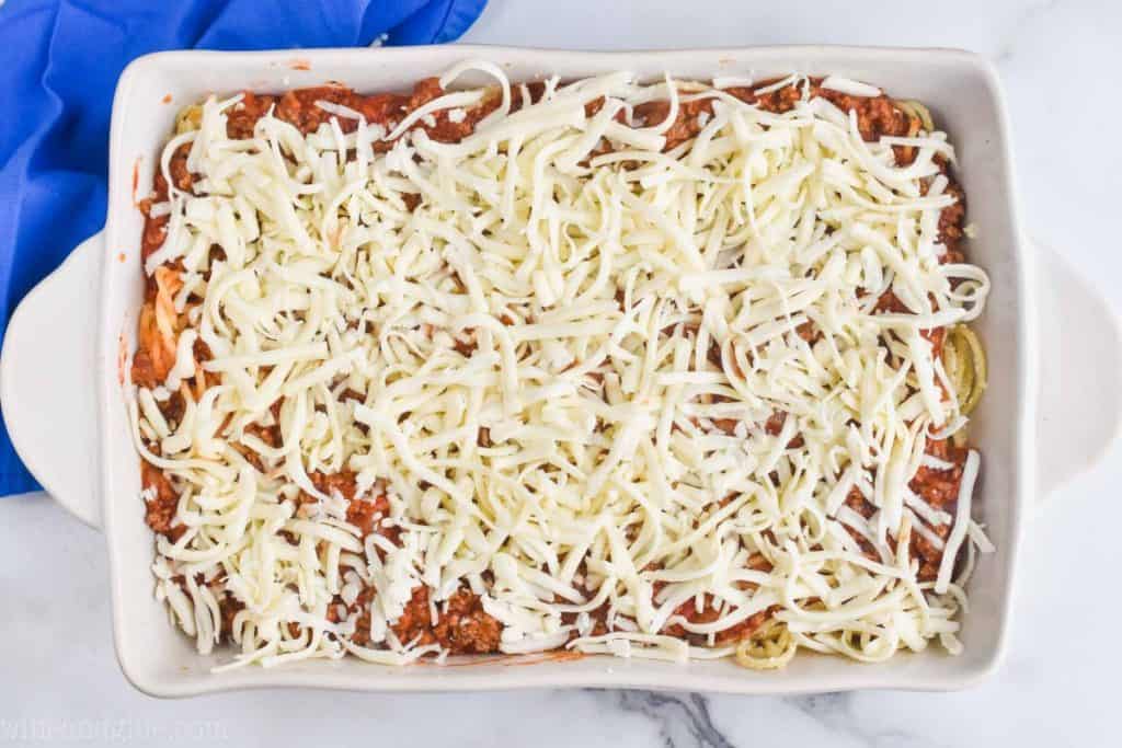 overhead of a baking dish full of baked spaghetti recipe with shredded mozzarella on top