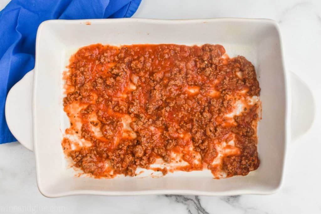 overhead view of a ceramic baking dish with a small amount of meat sauce at the bottom