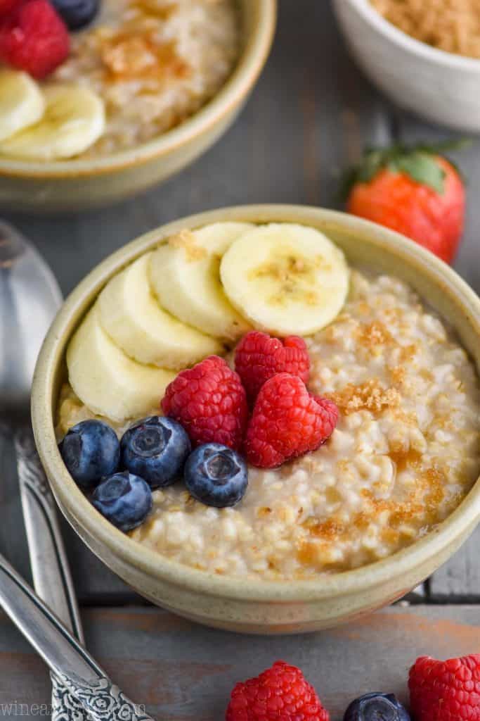 small bowl of steel cut oats with raspberries, sliced bananas, blueberries and a little brown sugar