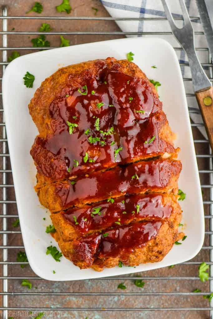 overhead view of a turkey meatloaf on a white plate that has been sliced a little and topped with fresh parsley
