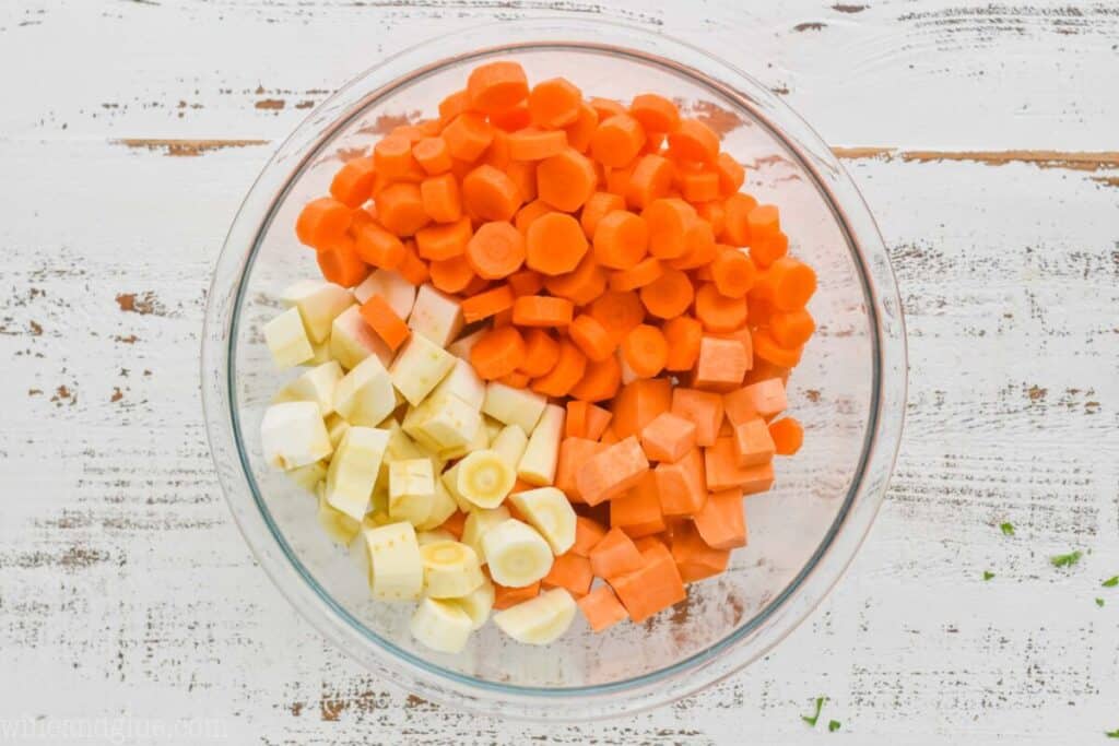 overhead view of a bowl full of raw cut up parsnips, carrots, and sweet potatoes