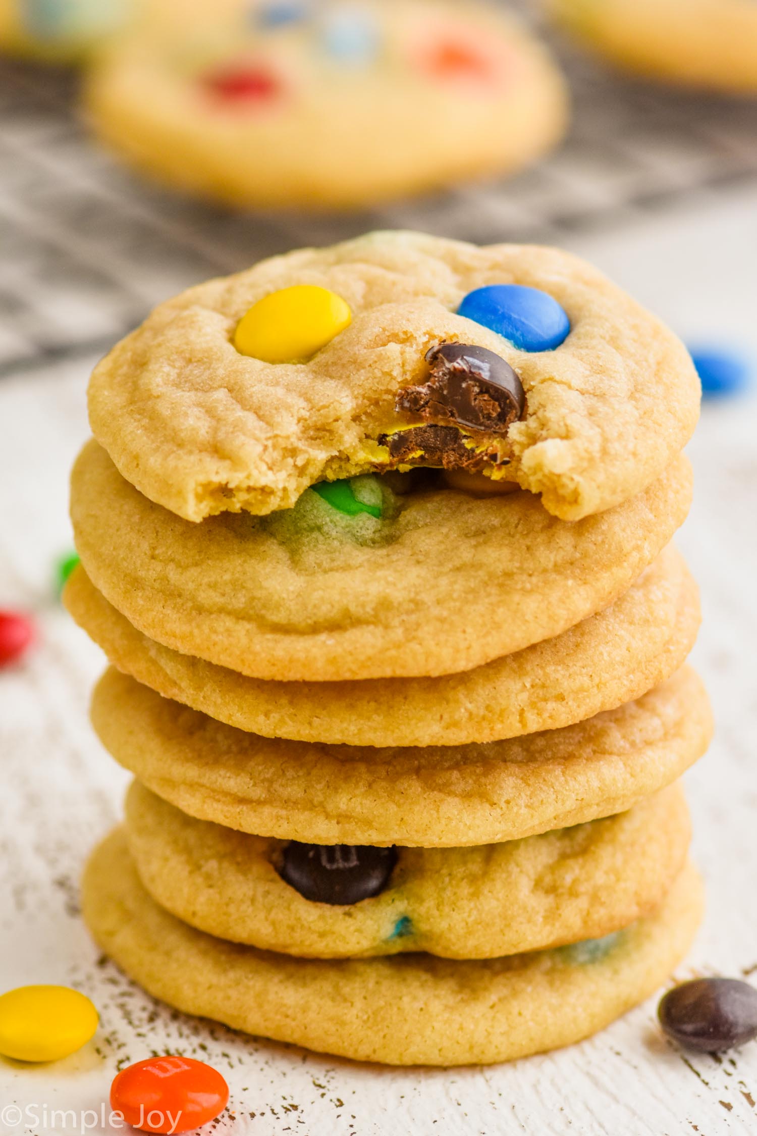 stack of M&M cookies recipe with the top cookie missing a bite