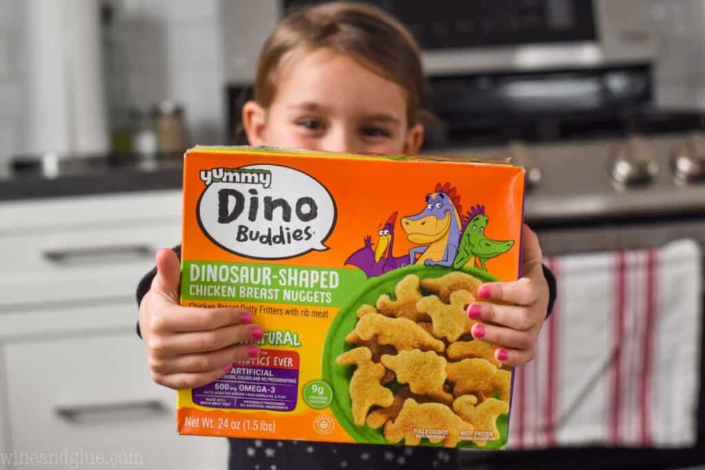 little girl holding a box of yummy Dino buddies