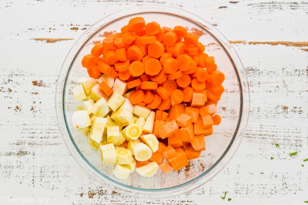 overhead view of a bowl full of raw cut up parsnips, carrots, and sweet potatoes