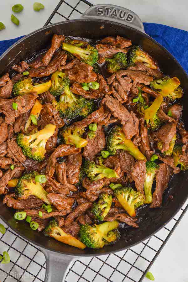overhead photo of a gray skillet filled with beef and broccoli recipe, garnished with sliced green onions