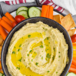 pinterest graphic of overhead of bowl of hummus dip surrounded by vegetables and pita chips, says: the best hummus recipe simplejoy.com