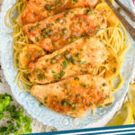 pinterest graphic of overhead of a blue plate with spaghetti topped with lemon chicken piccata, says: "chicken piccata simplejoy.com"