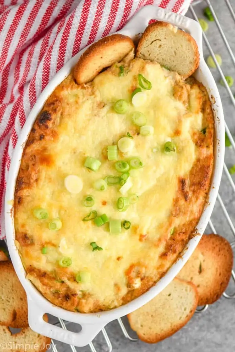 overhead view of crab dip recipe in a white casserole dish with two bagel chips sticking out of it