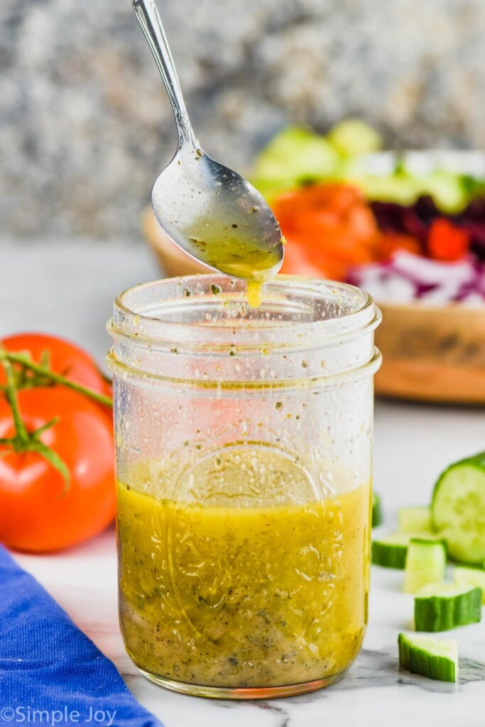 spoon dripping greek dressing into a mason jar