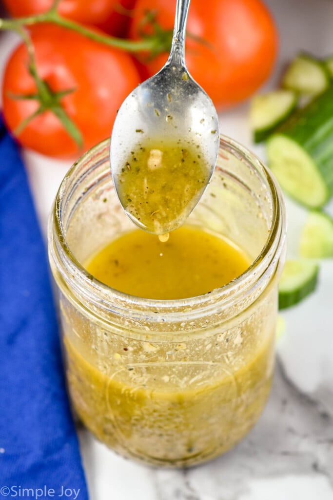 overhead view of spoon dripping greek dressing recipe into a mason jar