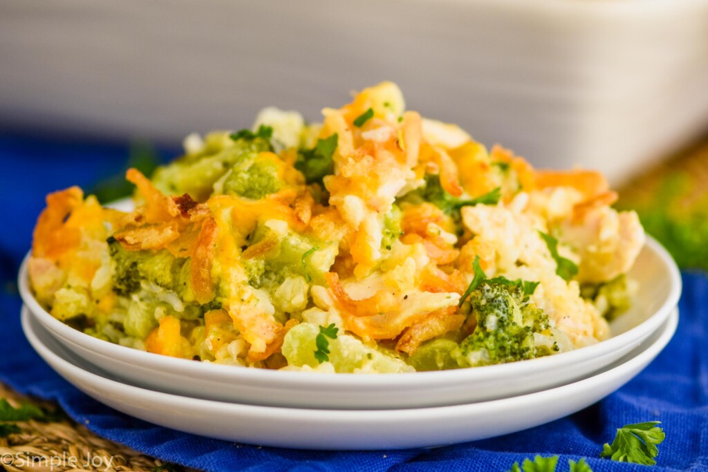 two white stacked plates with cheese chicken broccoli rice casserole on it