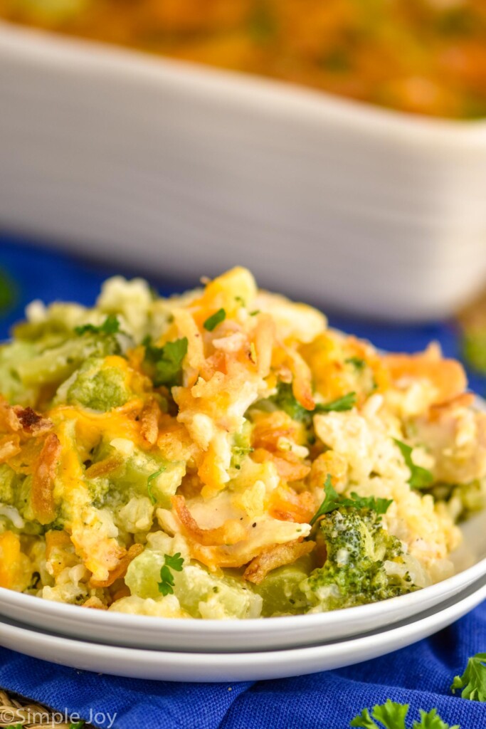 two white plates stacked with chicken rice broccoli casserole on it