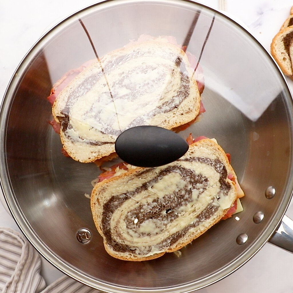 two reuben sandwiches in a frying pan covered