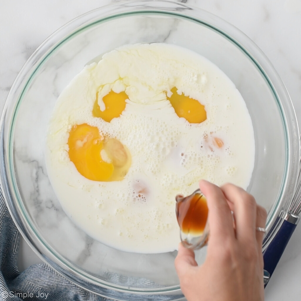 overhead of vanilla being poured into a bowl of cream and eggs