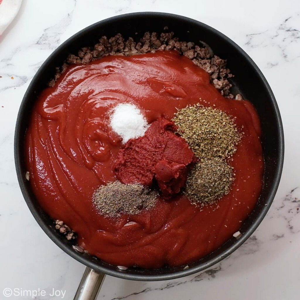 overhead photo of a skillet with cooked ground beef, sauce, and seasonings