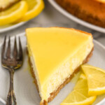 Overhead photo of a slice of Lemon Cheesecake served on a plate with a fork, garnished with lemon slices.