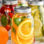 four mason jars filled with water and fruit to make infused water recipes