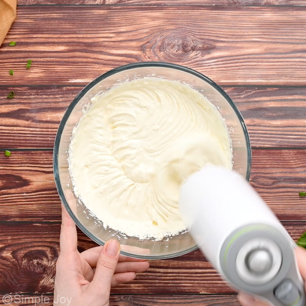 cream cheese mixture being blended together with a hand mixer