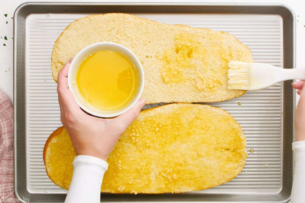 melted butter with garlic in it being spread over bread