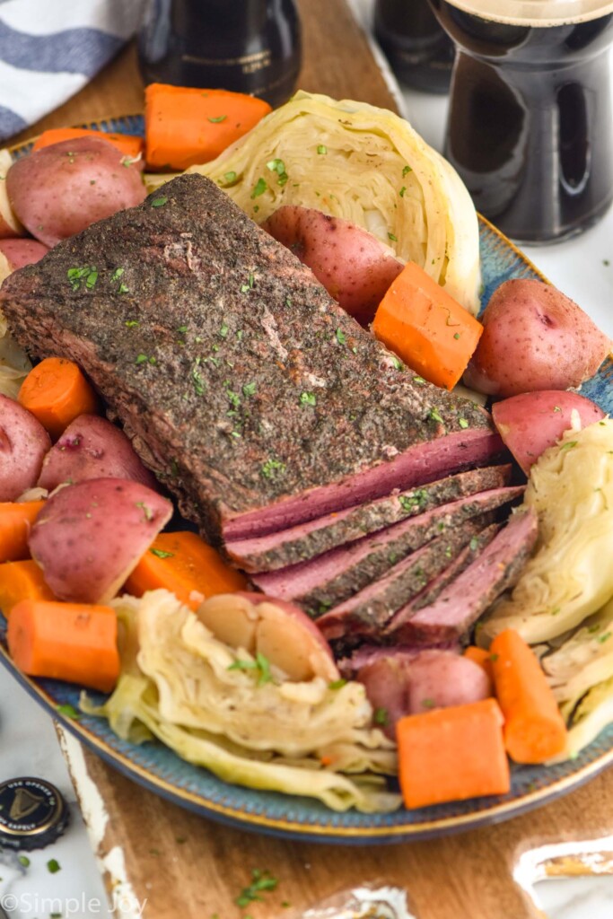 Instant Pot Corned Beef sliced on a platter with cabbage, potatoes, and carrots.