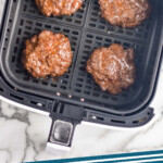 Pinterest graphic for Air Fryer Burgers recipe. Image shows air fryer basket with Air Fryer Burgers. Text says, "Air Fryer Burgers simplejoy.com"