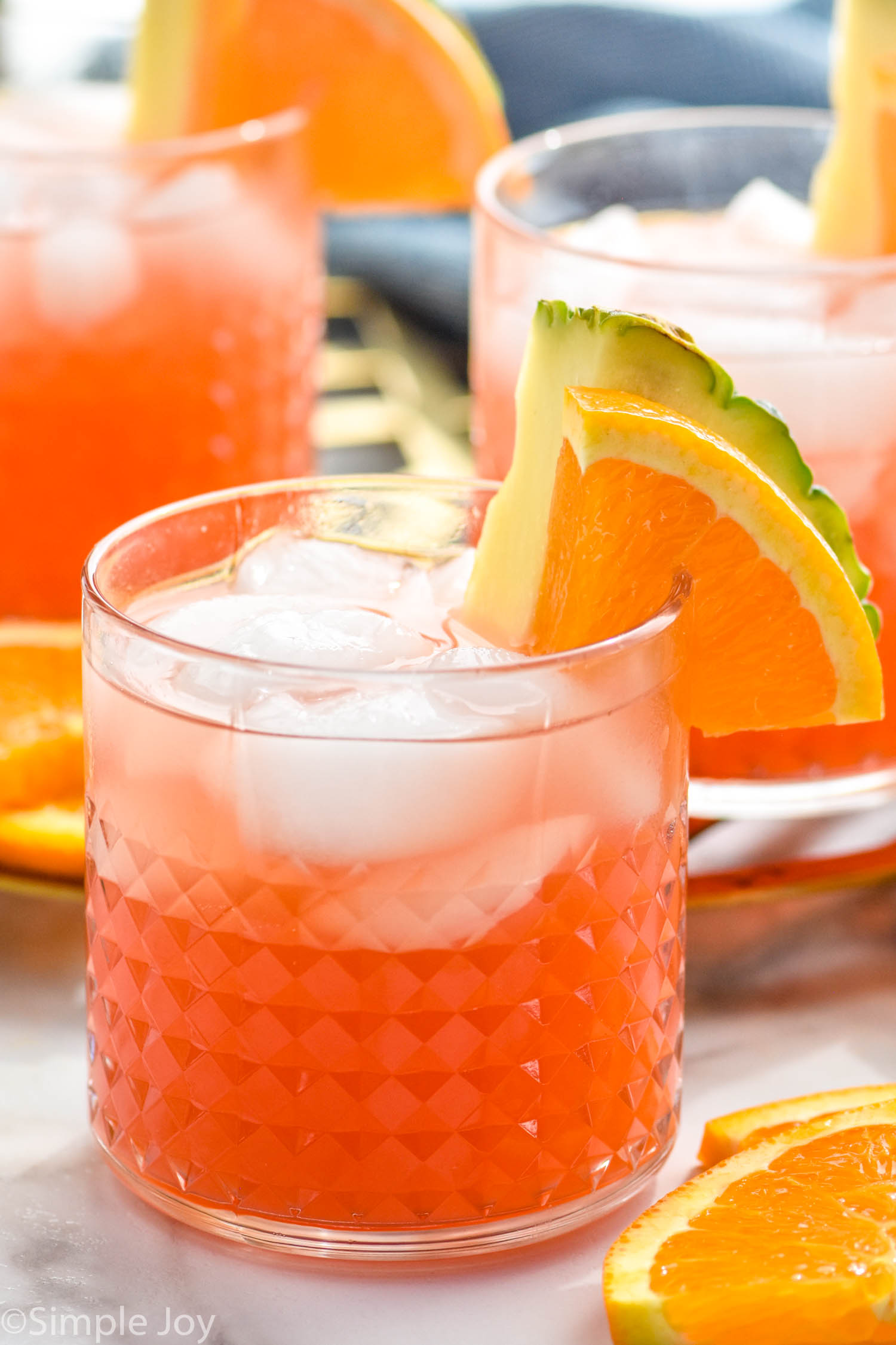 Glasses of rum punch with ice, garnished with orange slice and pineapple wedge