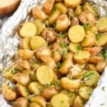 grilled potatoes in foil garnished with shredded cheese and parsley