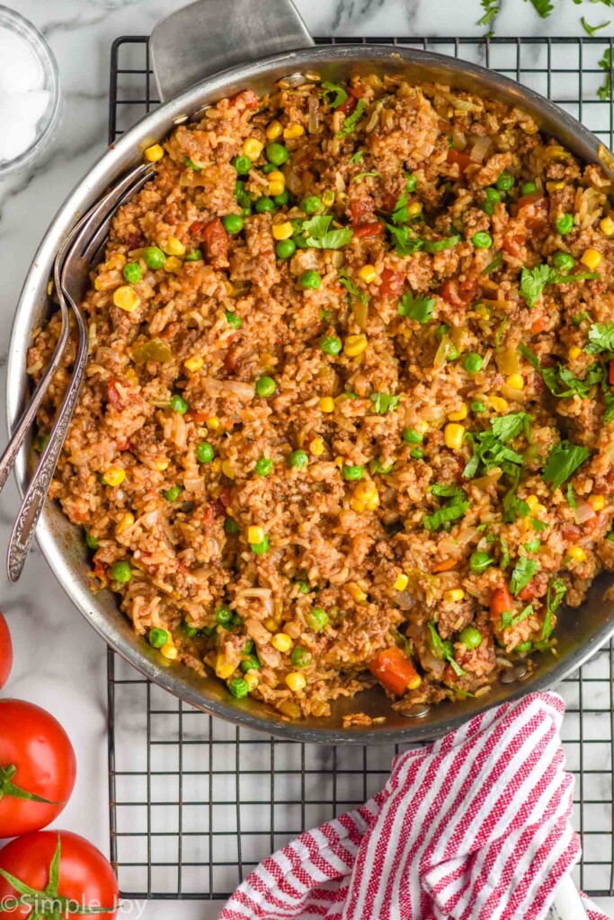 Overhead view of a large skillet of Ground Beef and Rice, garnished with cilantro with two large serving forks