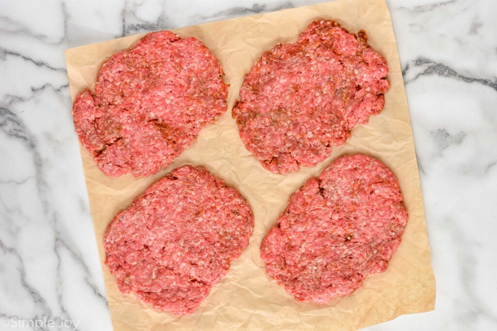 overhead of four ground beef patties to make patty melts