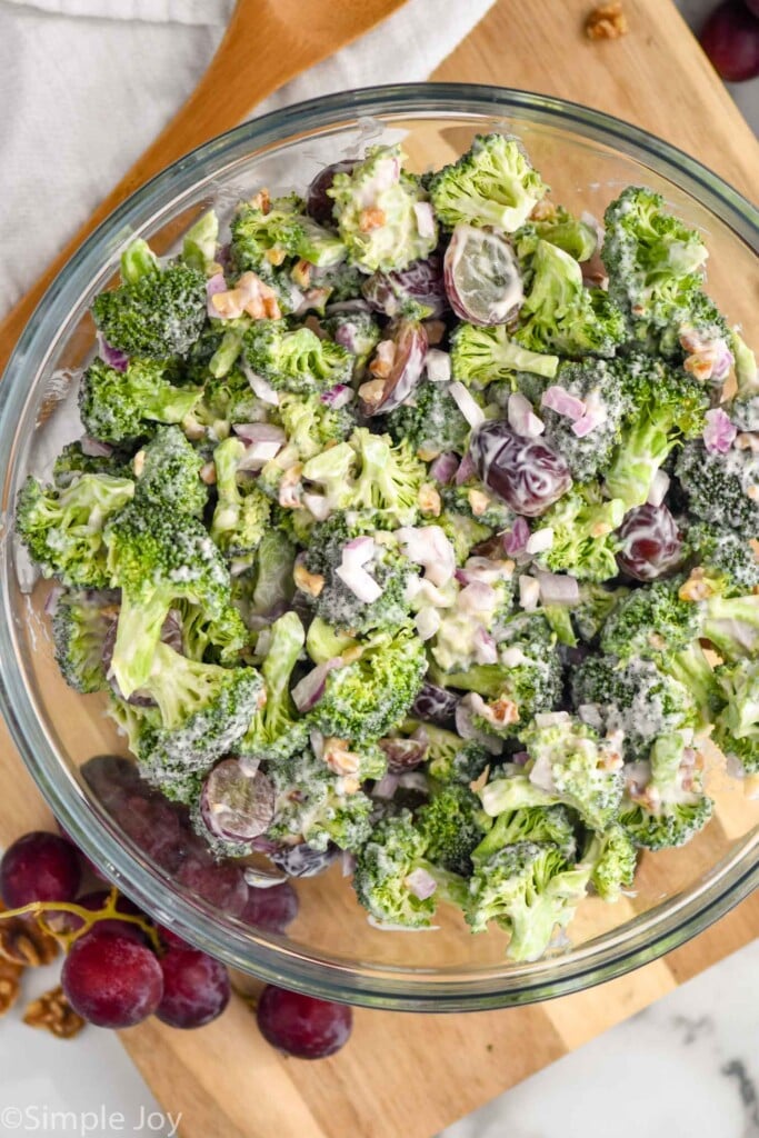 Overhead view of glass bowl of Broccoli Salad with grapes beside.
