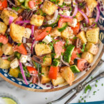 Pinterest graphic for Greek Panzanella Salad. Image shows overhead of bowl of Greek Panzanella Salad with tomatoes and serving tongs sitting beside Text says "greek panzanella simplejoy.com"