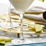 Pinterest graphic for Key Lime Martini recipe. Image shows two Key Lime Martinis garnished with slice of lime. Additional lime slices beside. Text says, "Key Lime Martini simplejoy.com."
