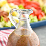pinterest graphic of close up bottle of red wine vinaigrette with Cobb salad behind it and blue cheese and green onions around it, says: "the best red wine vinaigrette"