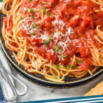 Pinterest graphic for Spaghetti Sauce recipe. Image shows a plate of spaghetti with Spaghetti Sauce, garnished with parmesan cheese and basil. Glass of red wine, salad, forks, and bread beside. Text says, "Spaghetti Sauce simplejoy.com"