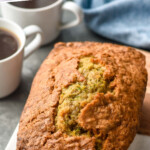 Pinterest graphic for Zucchini Bread. Text says "the best Zucchini Bread simplejoy.com" Image shows loaf of Zucchini Bread on a cutting board with two mugs of coffee in background