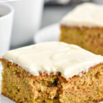 Pinterest graphic for Zucchini Cake recipe. Text says, "the best Zucchini Cake simplejoy.com" Image shows a piece of frosted Zucchini Cake on a plate with a fork beside.